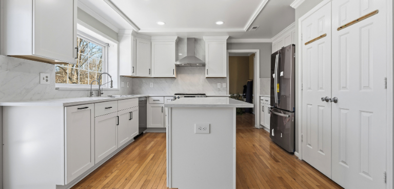 Modern kitchen remodeling featuring light gray shaker cabinets, white quartz counter tops, and a breakfast bar.
